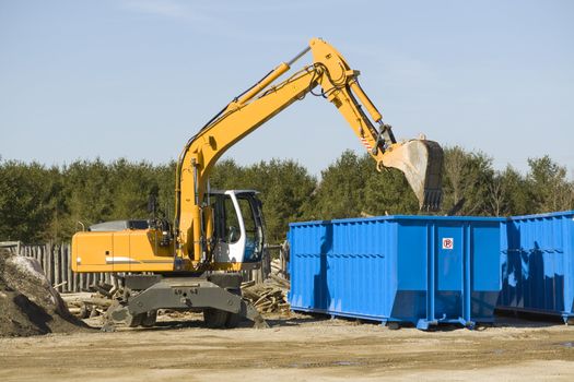 yellow demolition bulldozer beside a dumpster