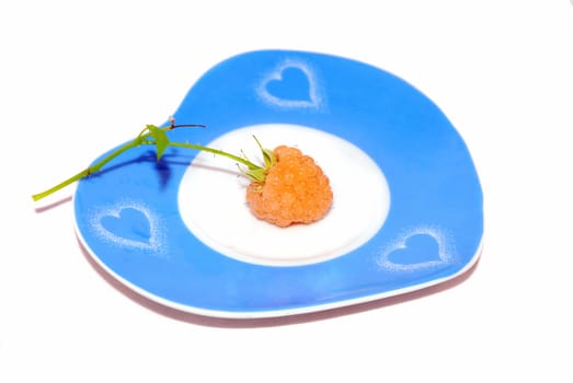 One yellow raspberry on the nice bue heart plate isolated on the white. 