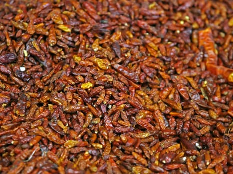 Small dried red hot chili peppers in market background 