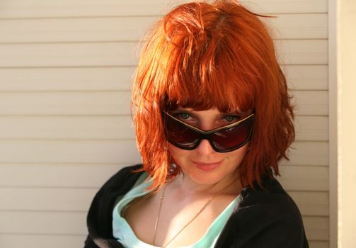 The girl with red hair in solar glasses