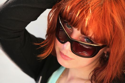 The girl with red hair in solar glasses