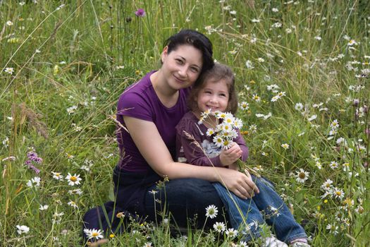 The little girl with mum and with camomiles