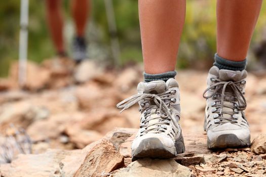 Hiking shoes close up outoors during hike - female shoes. Hikers in the background