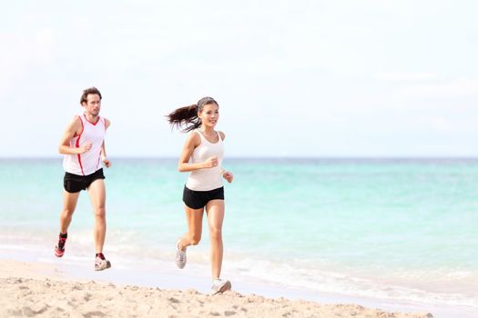 Couple running on beach. Runners jogging outside training. Caucasian / Asian woman runner and Caucasian fitness man model.