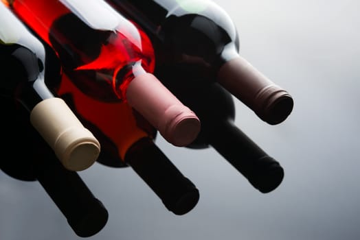 three bottles with wine on a table with a reflection