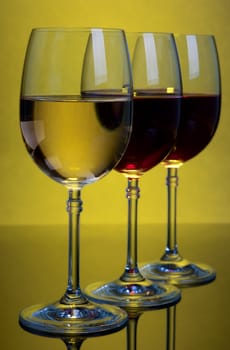 Glasses with wine on a yellow background .