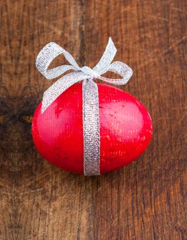 Wooden red painted egg with bow and ribbon on old wooden background