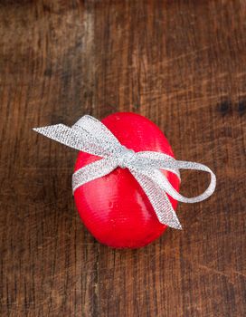 Wooden red painted egg with bow and ribbon on old wooden background