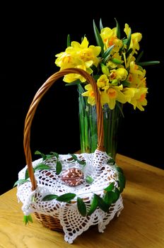 Basket with Easter eggs and daffodils on a table