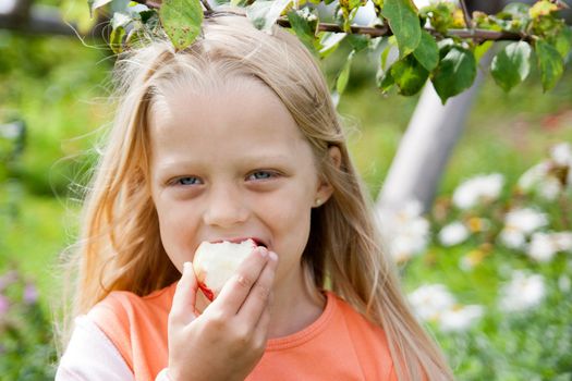 Happy little girl holding apple in her hands