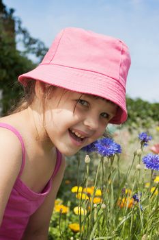 Little girl and flowers in summer meadow