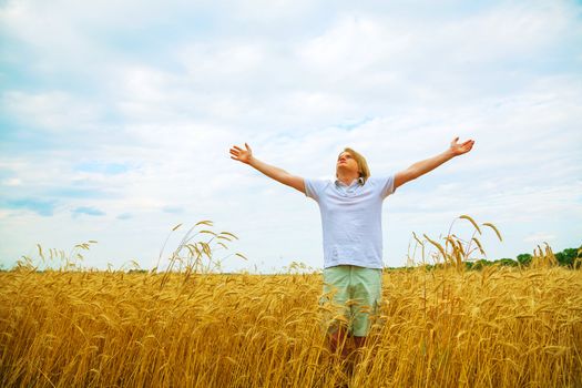 Young man staying with raised hands at sunset time