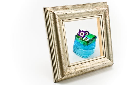 Picture frame in front of flowers in blue vase isolated on white