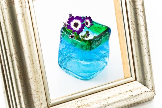 Picture frame in front of flowers in blue vase isolated on white