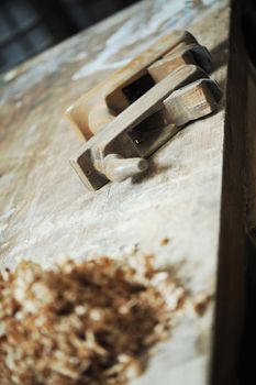 a work table of a carpenter with two hand planers and a pile of wood chips