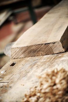 a work table of a carpenter with a wooden plank and a pile of wood chips