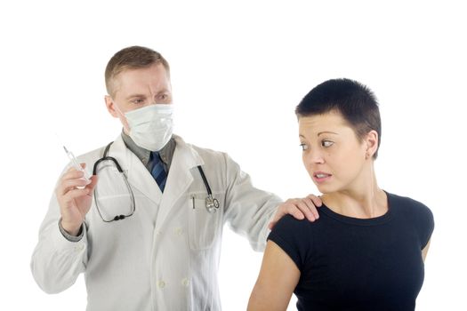 Doctor in gauze mask holds a frightened woman by her shoulder and prepares a syringe for an injection