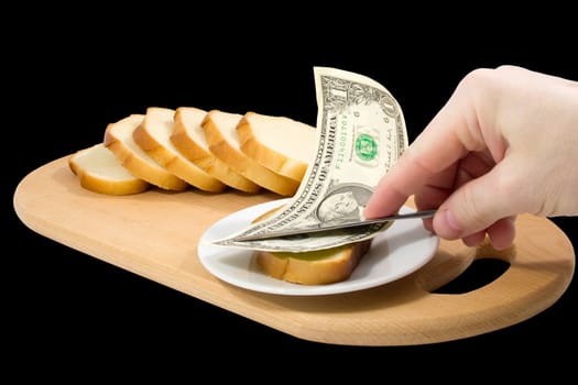 Hand spreads bread with one-dollar banknote on black background