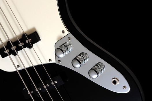 a close up of volume knob of a black electric bass glossy on dark background