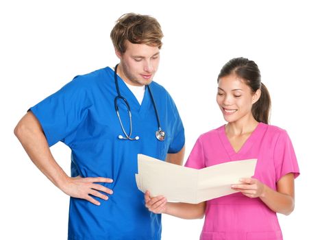 Medical nurses or doctors talking working together in team looking at file folder. Young man and woman medical professionals in scrubs isolated on white background. Asian female and Caucasian male in their twenties.