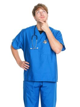 Male nurse thinking - man nurse or young doctor in blue scrubs looking up contemplative isolated on white background. Young Caucasian male medical professional.