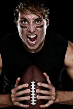 American football player screaming aggressive holding american football on black background. Strong fit Caucasian fitness man.