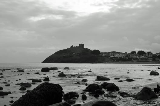 Picture from the seashore looking towards a castle on the coastline.