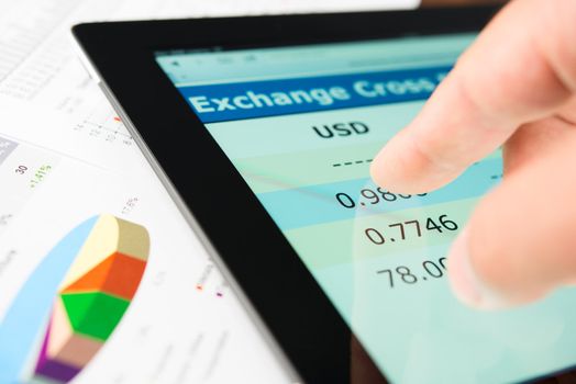 Hand on screen tablet pc with currency exchange information