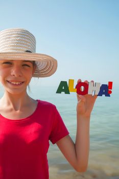 Teen girl at a beach holding word 'Aloha'