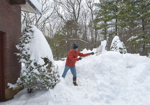 Senior citizen shoveling the walkway to his house