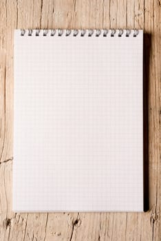 Blank white notepad on a hardwood floor lit on the side