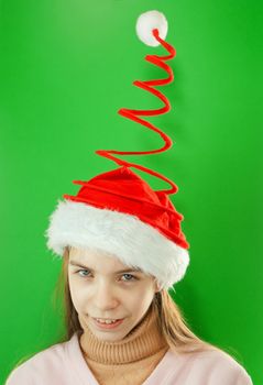 Pretty Santa girl, closeup portrait of a teen girl wearing Christmas hat against green background
