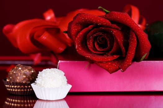 beautiful red roses with chocolates on a red background