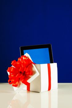 Tablet PC in a gift box against blue background