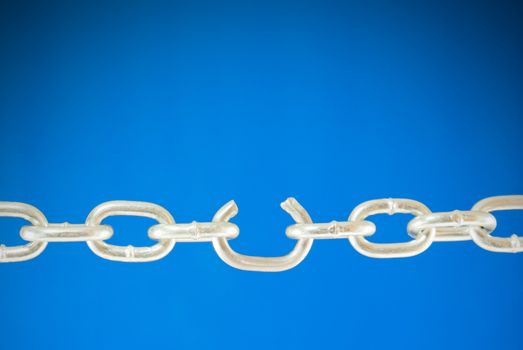 Steel chain with a broken link over blue background