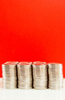 Coins stacked in bars against red background