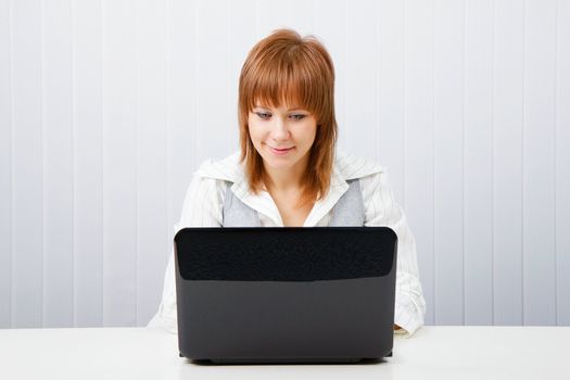 Attractive smiling girl with a laptop in the office