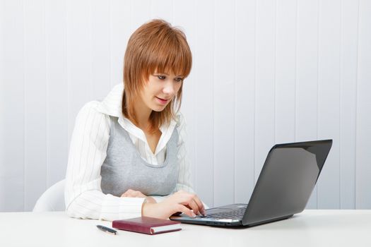 Attractive smiling girl with a laptop in the office
