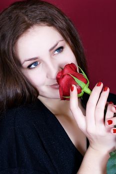 Beautiful woman enjoys the scent of red roses