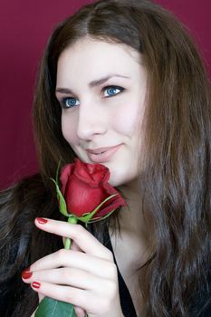 Beautiful woman enjoys the scent of red roses