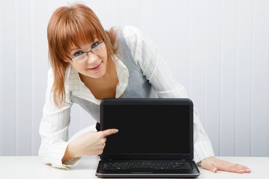 girl with glasses shows a finger on a laptop monitor. Close-up