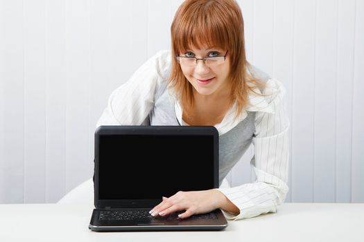 Attractive girl in glasses with a laptop in the office