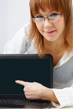 girl with glasses shows a finger on a laptop monitor. Close-up