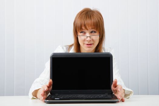 Attractive girl in glasses with a laptop in the office