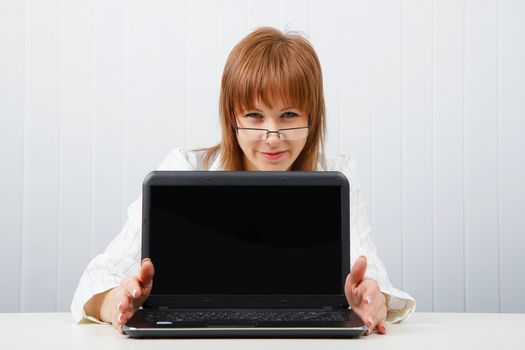 Attractive girl in glasses with a laptop in the office