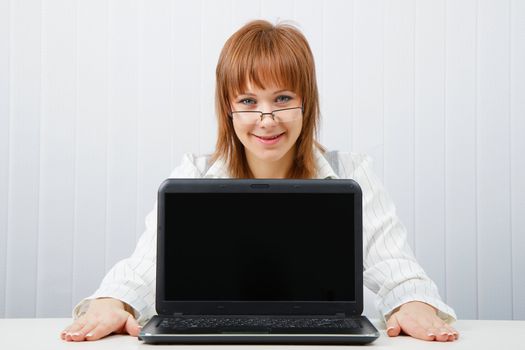 Attractive girl in glasses with a laptop in the office