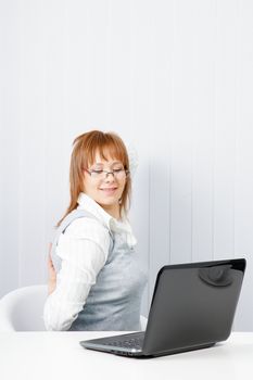 tired girl with a laptop stretches in the workplace