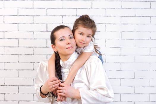 5 year old daughter in a white dress gently hugs his mom