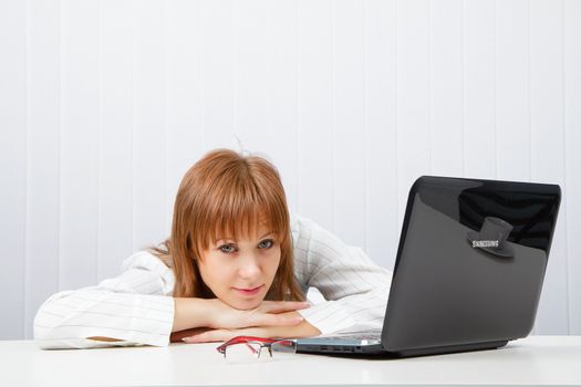 Tired girl lies on a table with a laptop