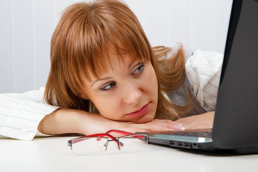 Tired girl lies on a table with a laptop